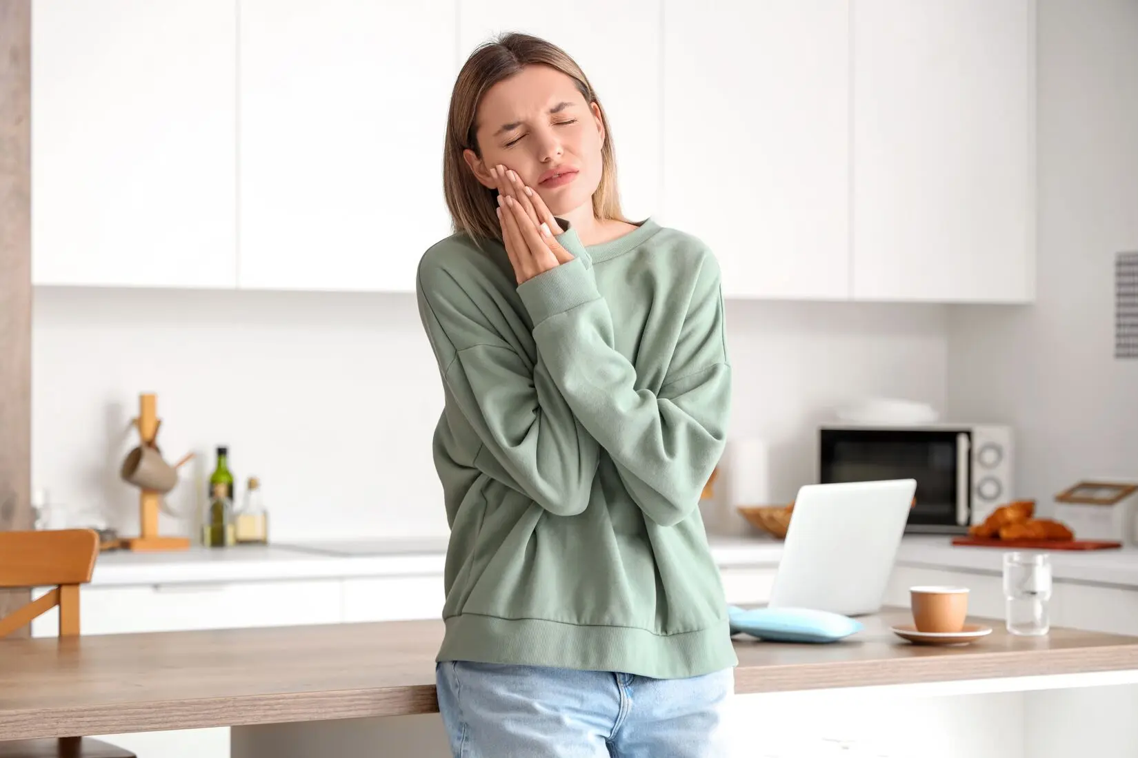 A woman touching her cheek from jaw discomfort