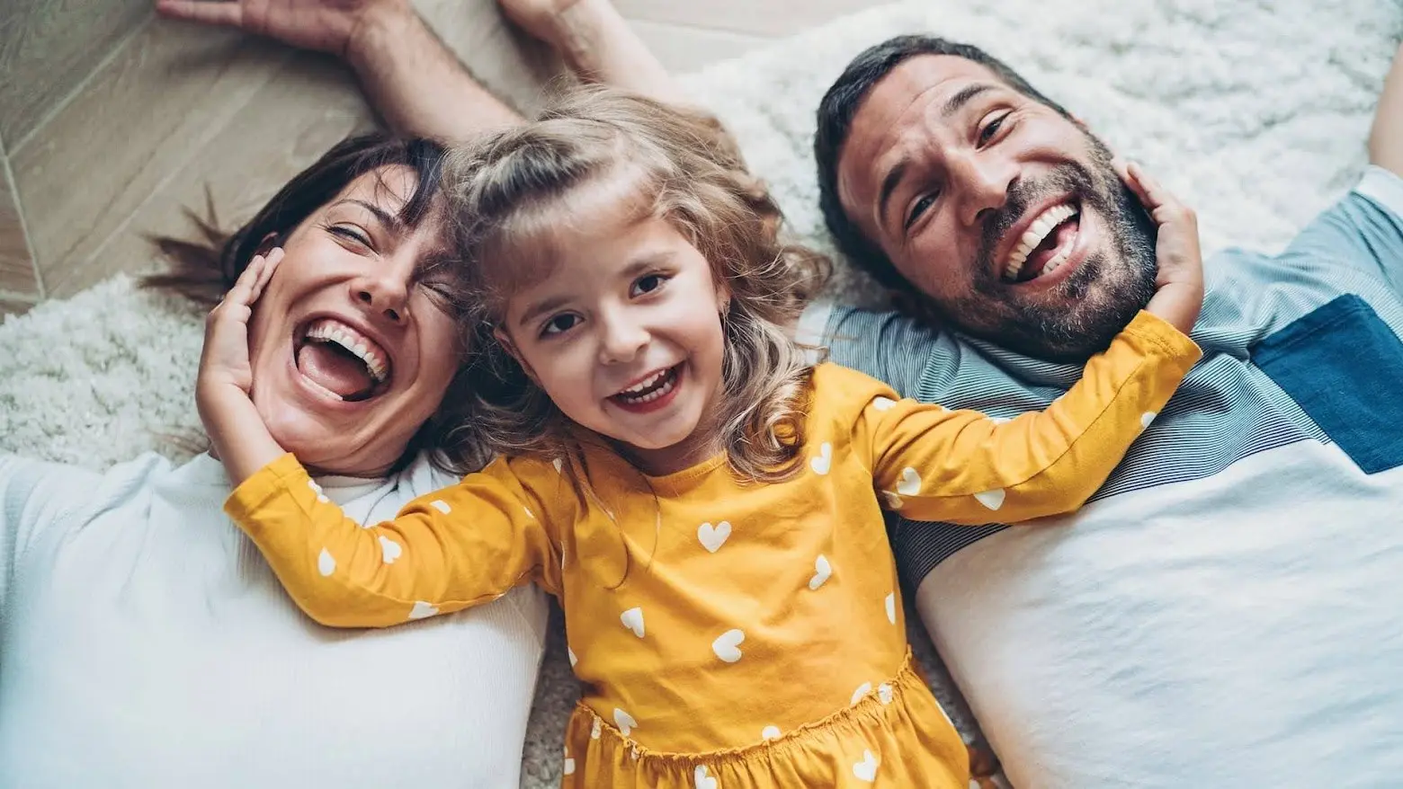 A young family lying on the floor laughing together