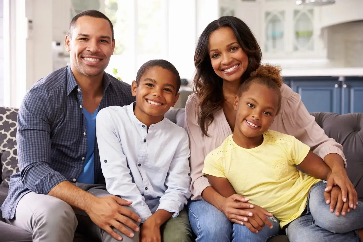A family of four smiling together on a sofa