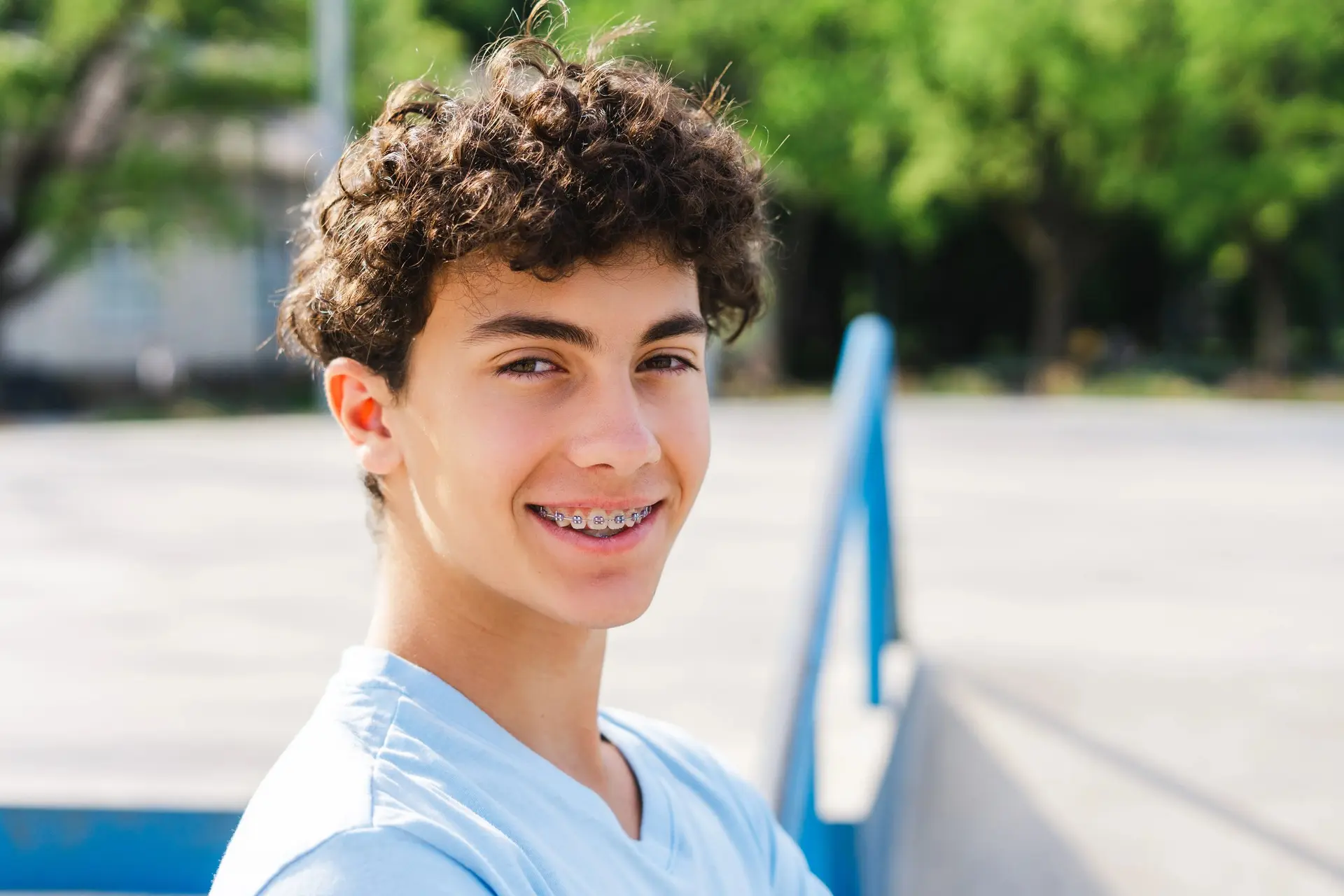 A teenager with braces smiling outdoors